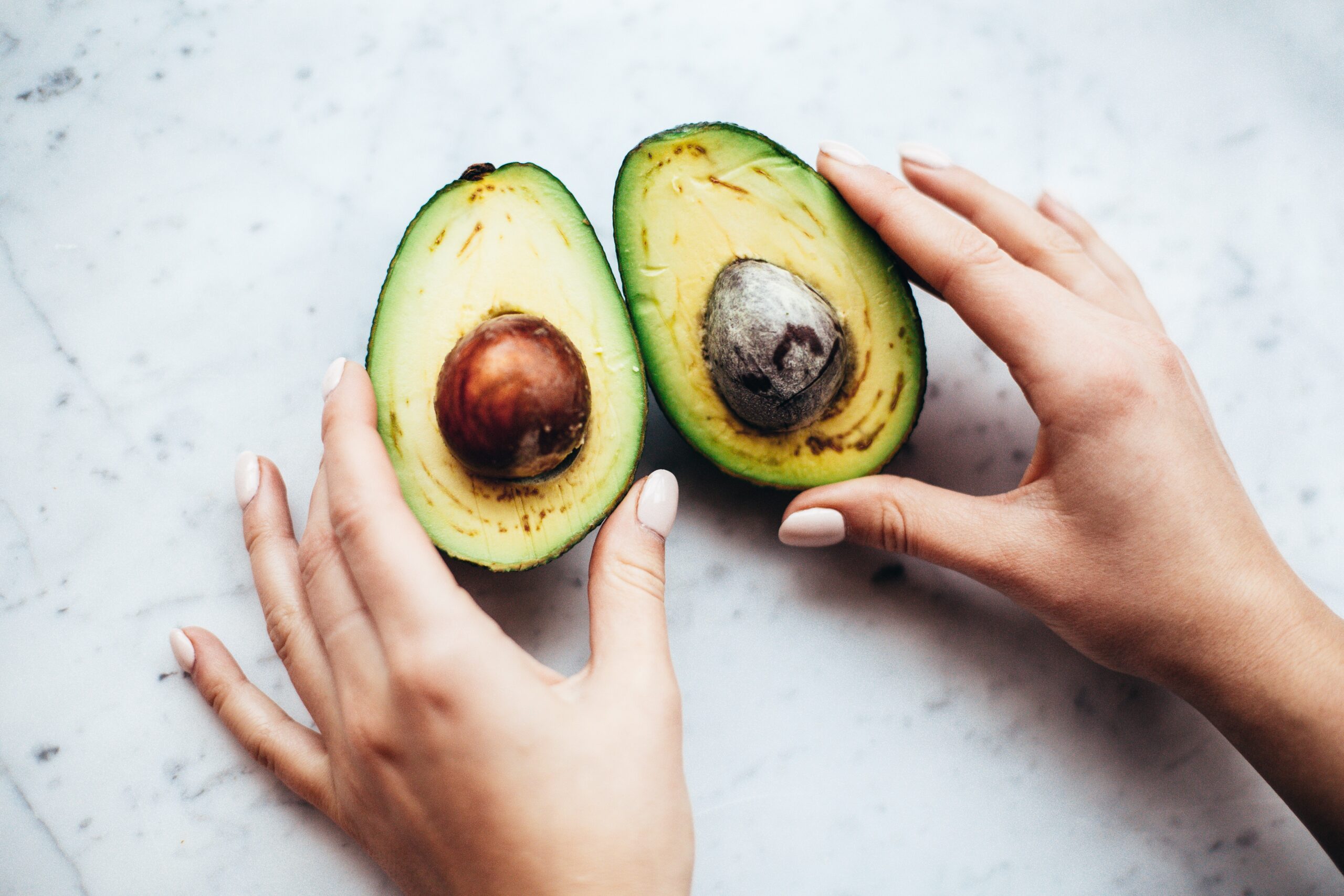 avocado turning brown cut in half stones inside with hands