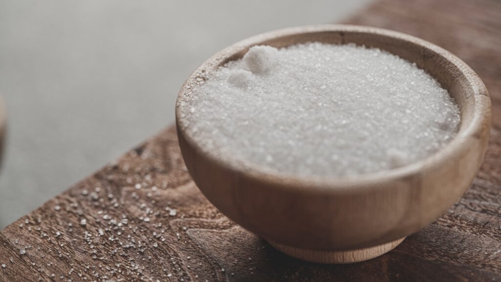 Wooden bowl of salt on wooden table, a little spilled / rustic / article how much is a pinch of salt